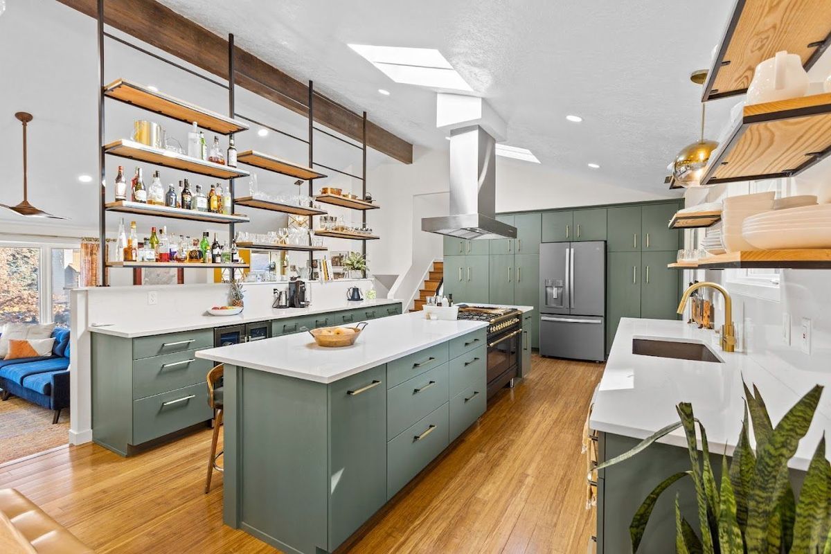 Modern kitchen with sage green cabinets, open shelving, and a large island.