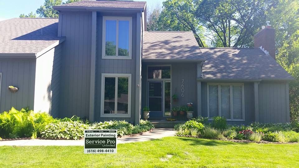 Gray house with large windows, manicured lawn, and a Service Pro sign.