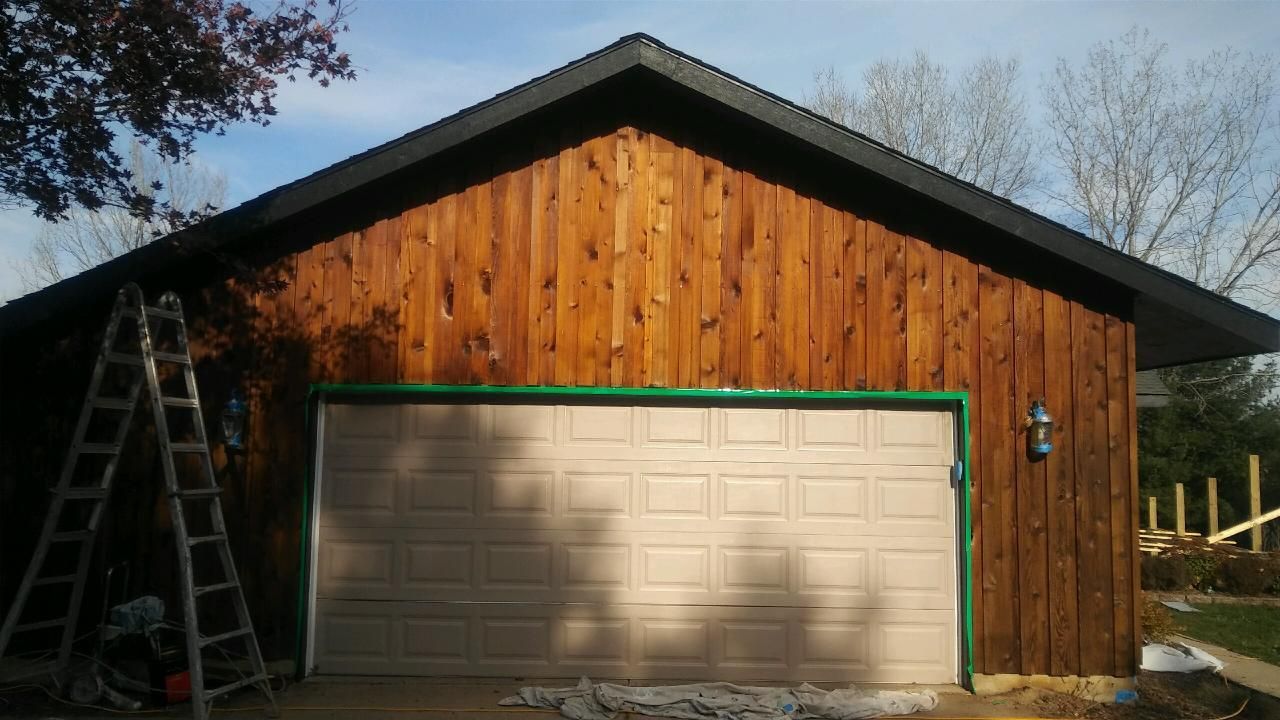 Brown garage with tan door, green trim, and ladder leaning against the side.