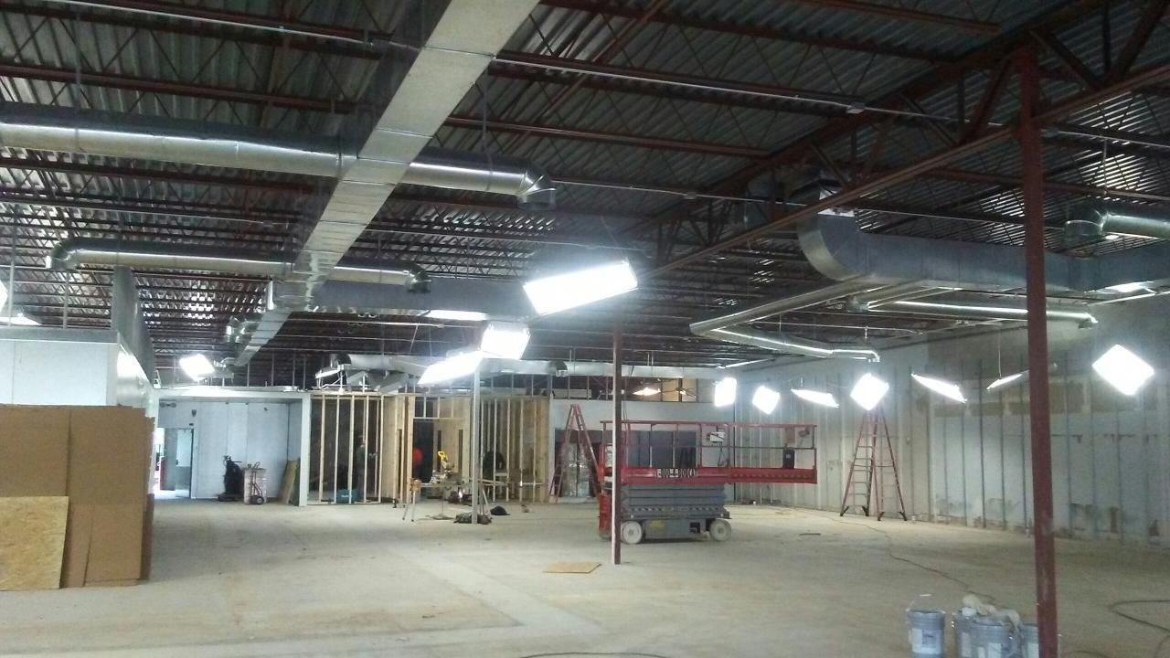 Interior of a large unfinished building. Exposed ductwork, studs, and construction materials.