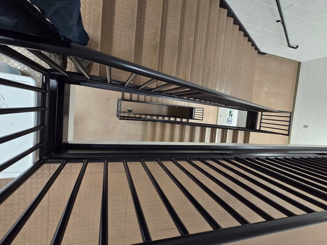Overhead view of a stairwell with black metal railings and beige carpeted stairs.