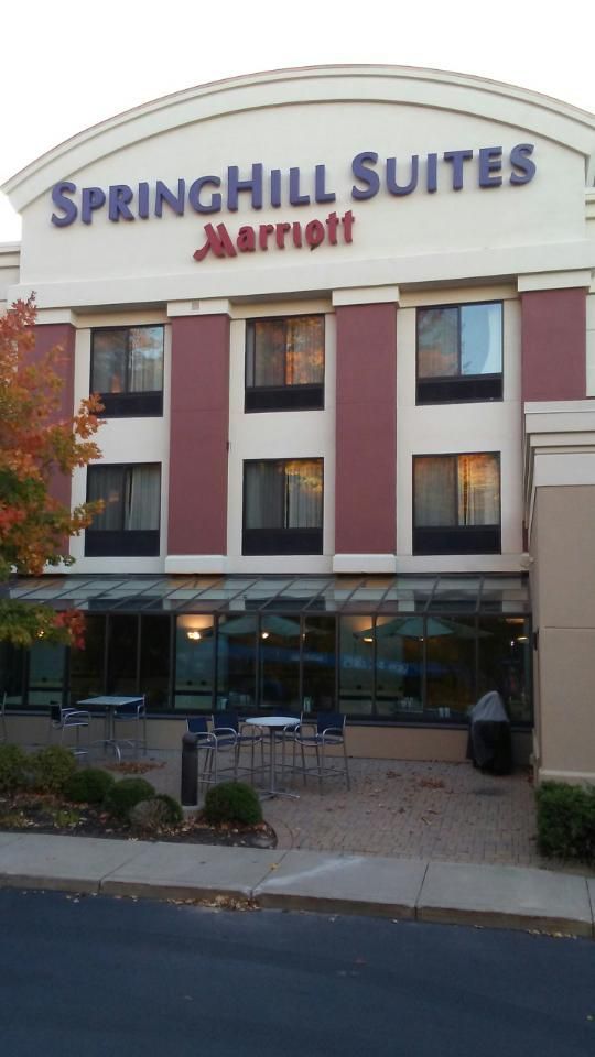 SpringHill Suites by Marriott building exterior with red and white panels, windows, and outdoor seating.