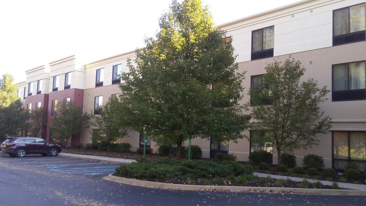 Hotel building with trees and a car parked in front.