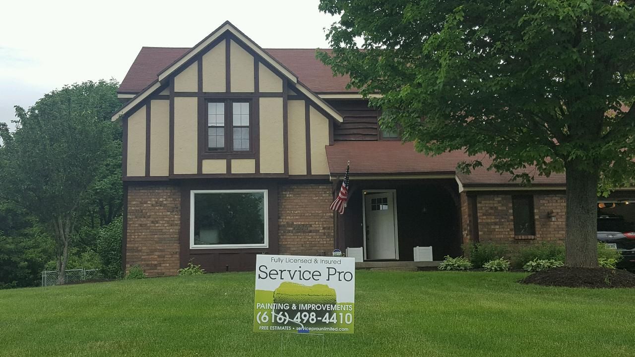 Tudor-style house with brown brick and beige stucco facade, a sign for 