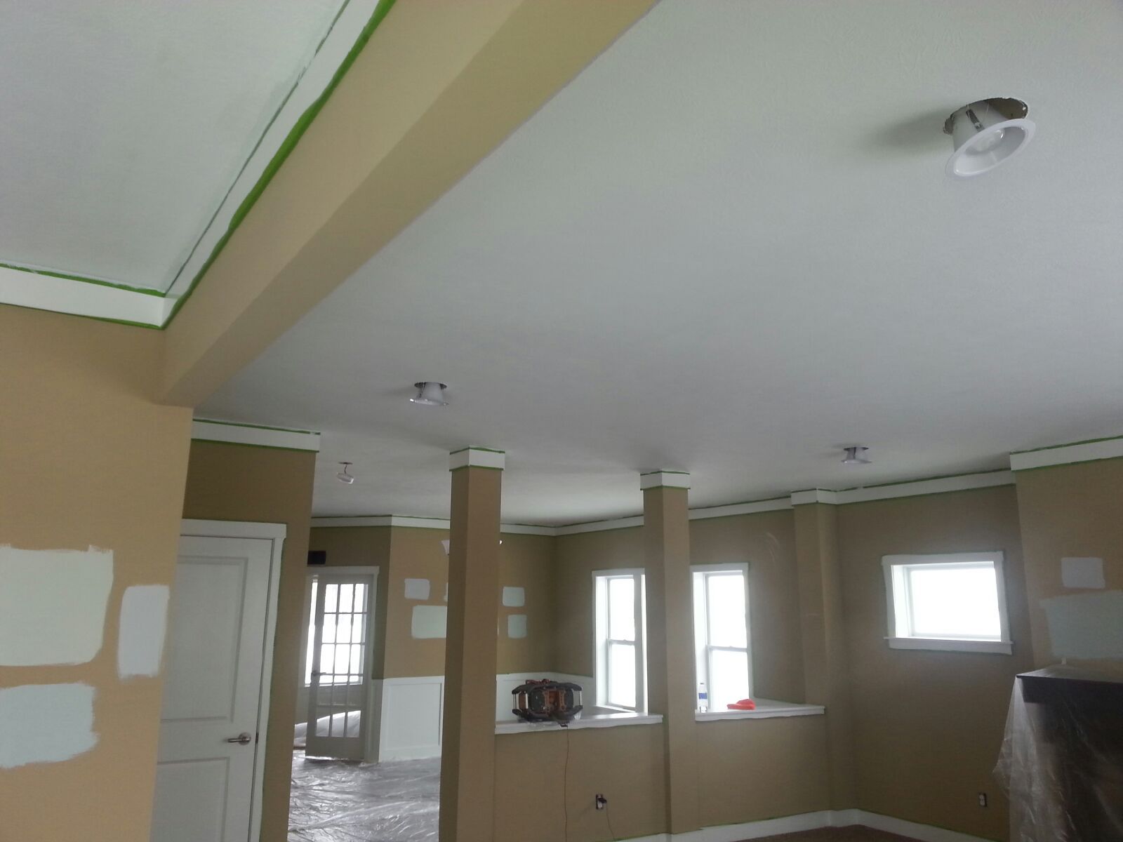 Interior room during renovation with beige walls, white ceiling and accents, three columns.