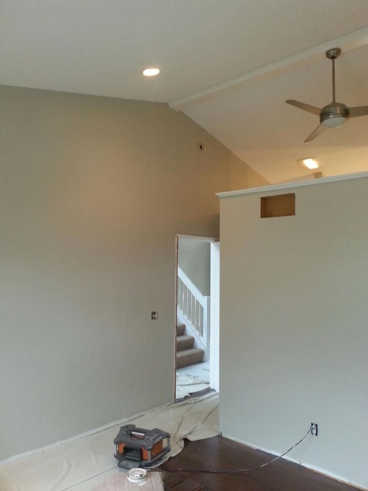 A room with light gray walls, white trim, and a partially open doorway leading to a staircase.