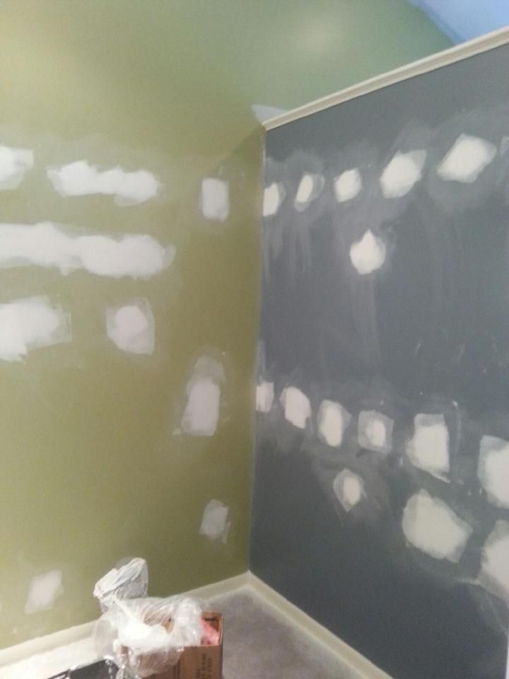 Green and gray walls with patches of white filler in a room being renovated.