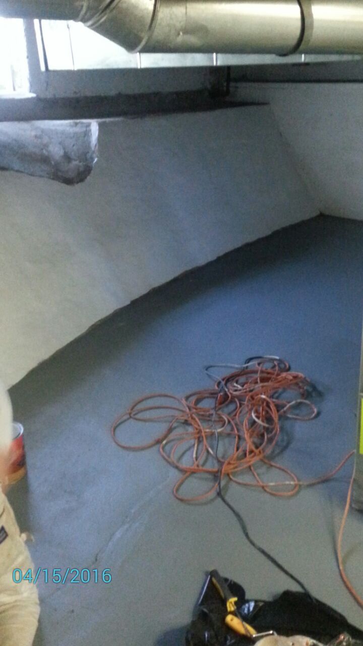 Grey-painted basement corner with coiled orange extension cord. Includes a black trash bag and ventilation pipe.