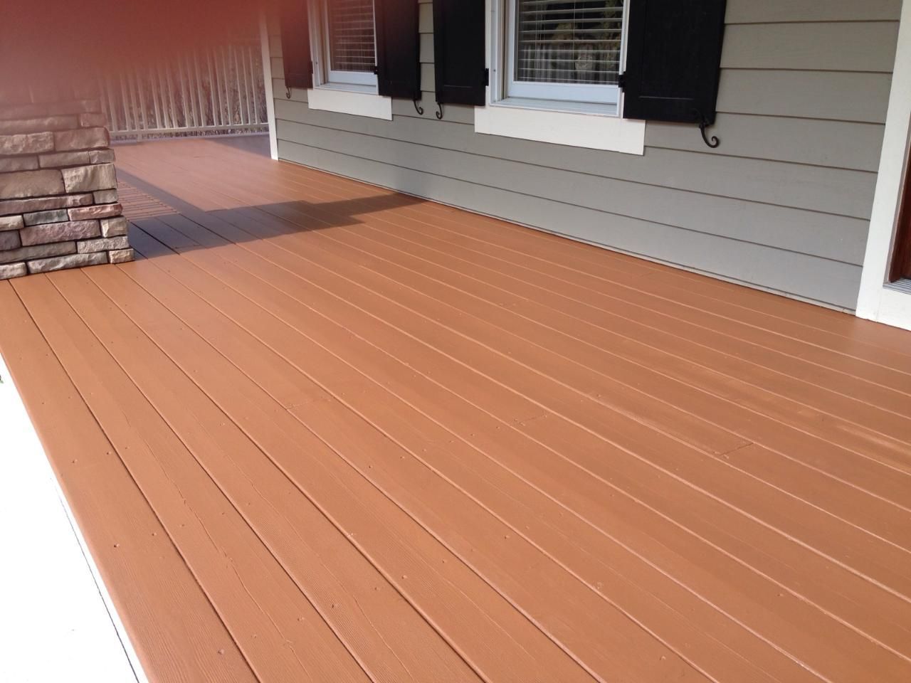 Brown composite deck of a house, gray siding, white trim, black shutters.