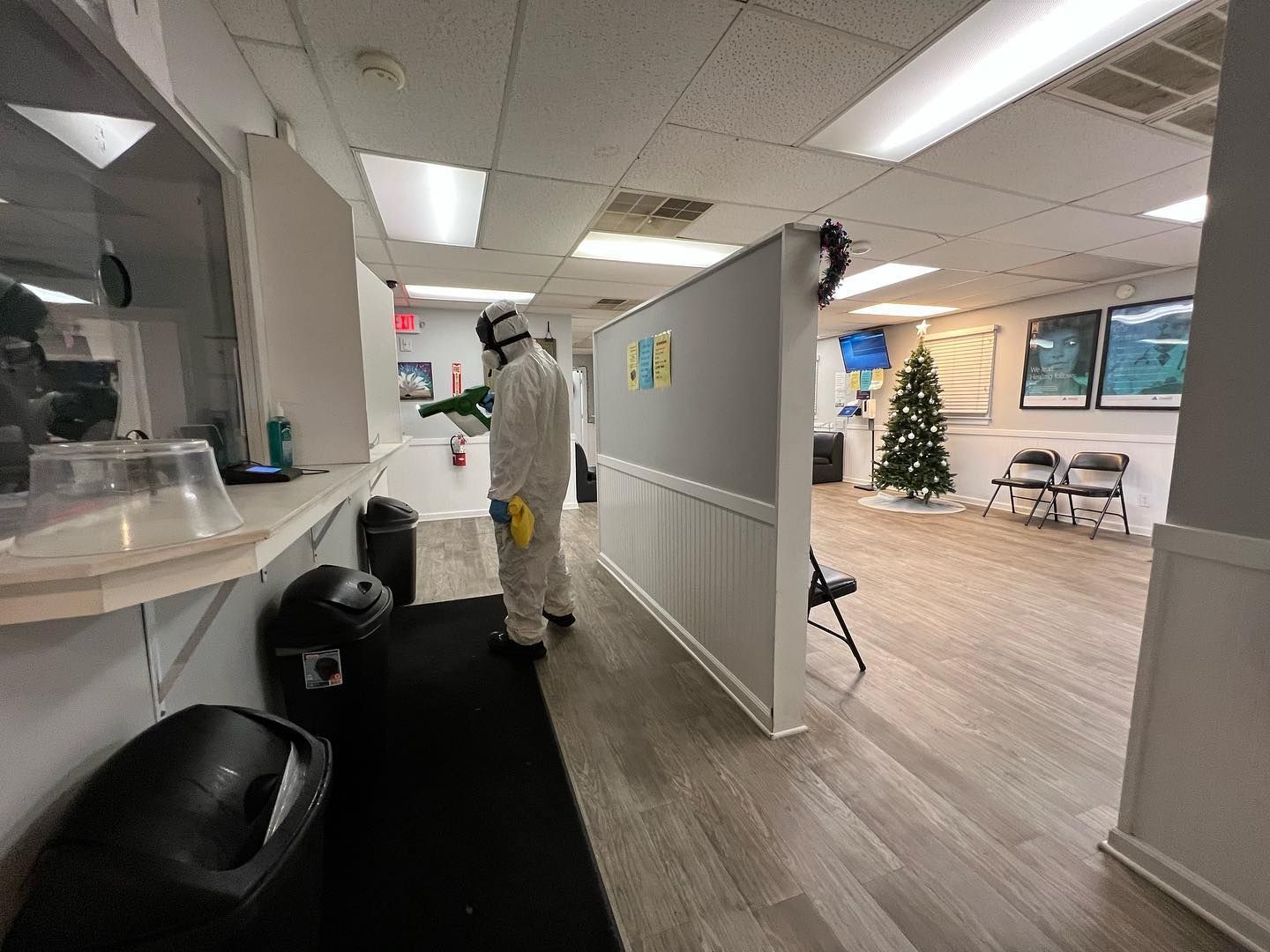 Person in protective suit disinfecting an office space with a sprayer.