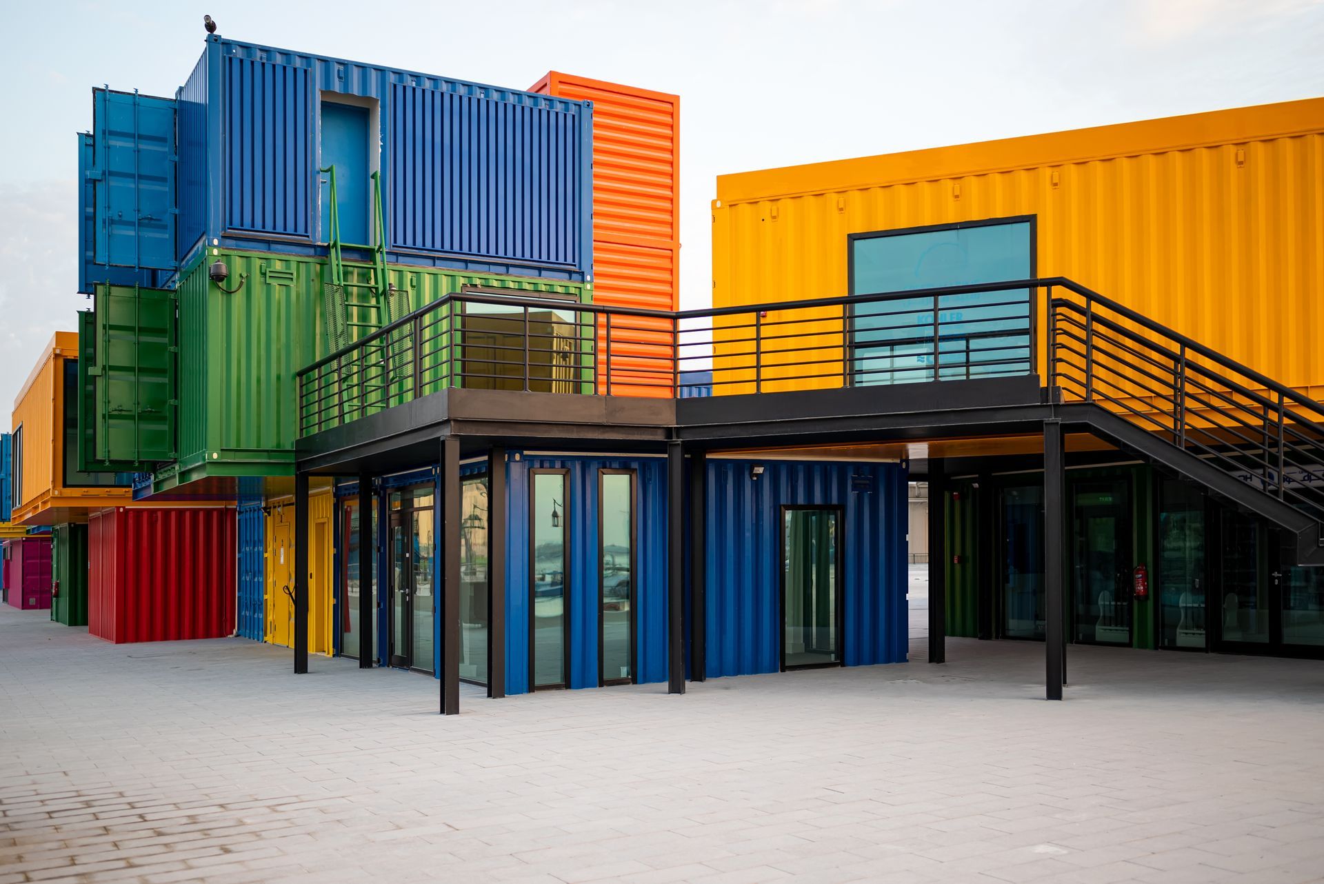 A row of colorful shipping containers with stairs leading up to them.