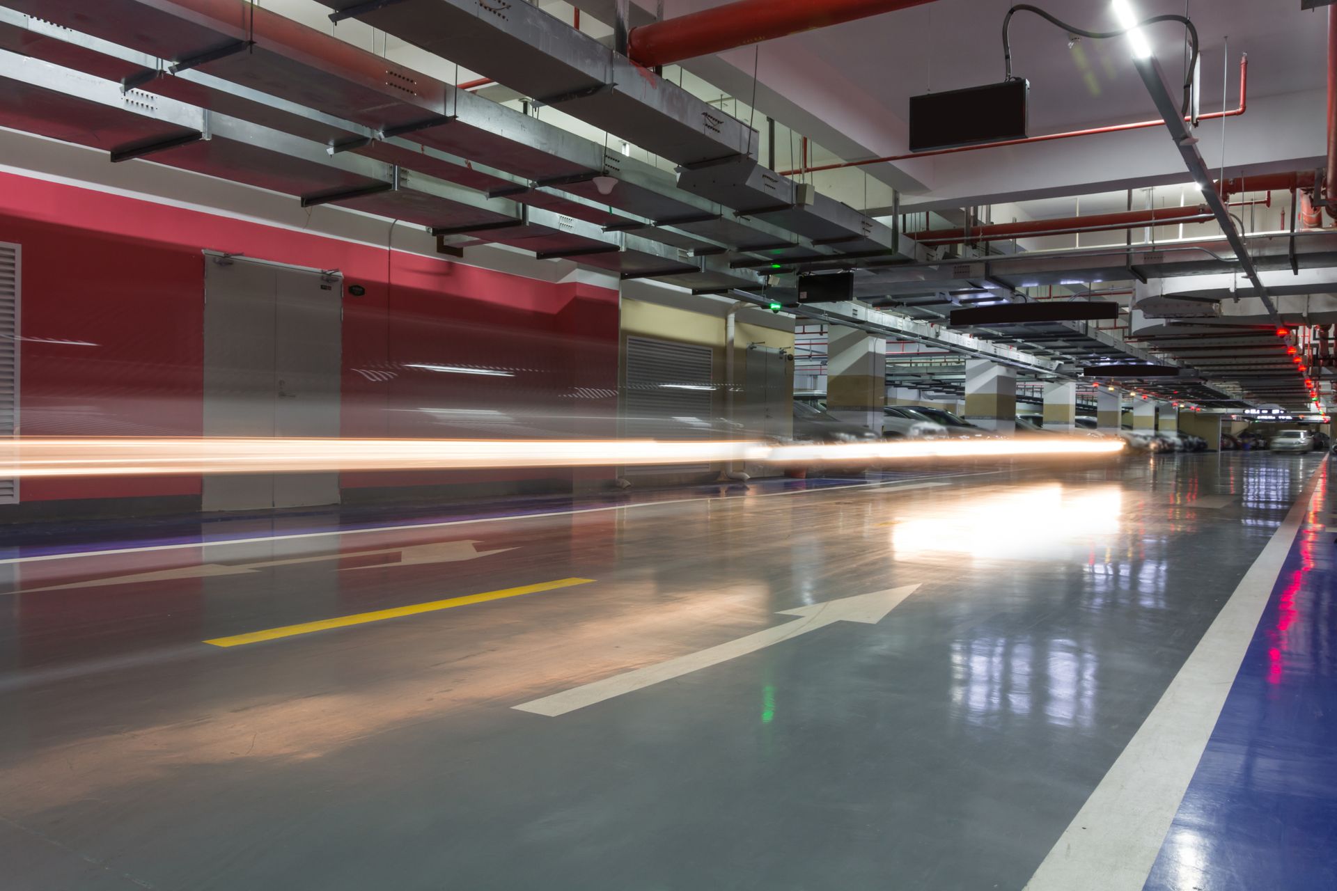 A long exposure photo of a parking garage with cars driving through it.