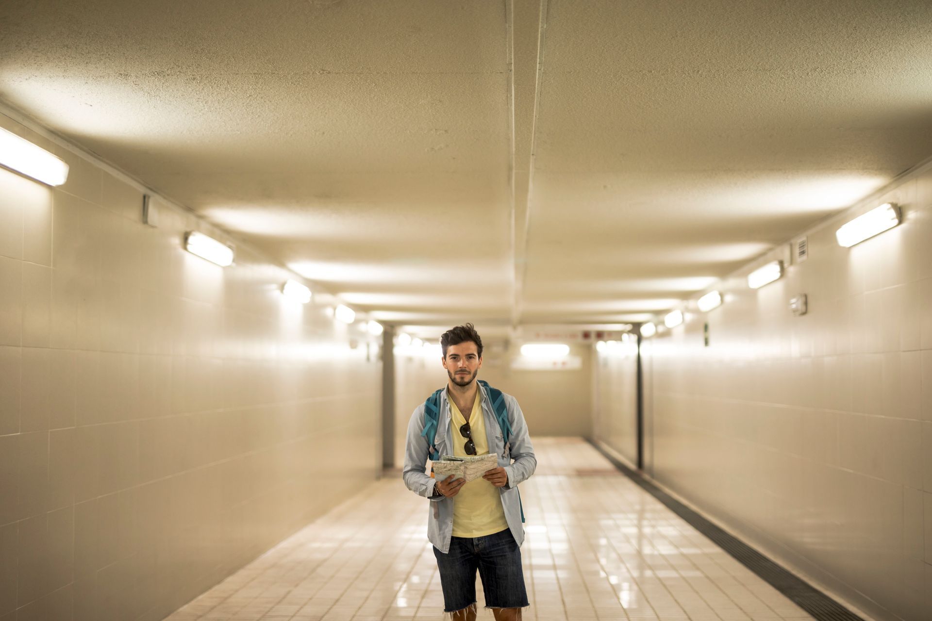 A man is standing in a lit-up tunnel holding a book.