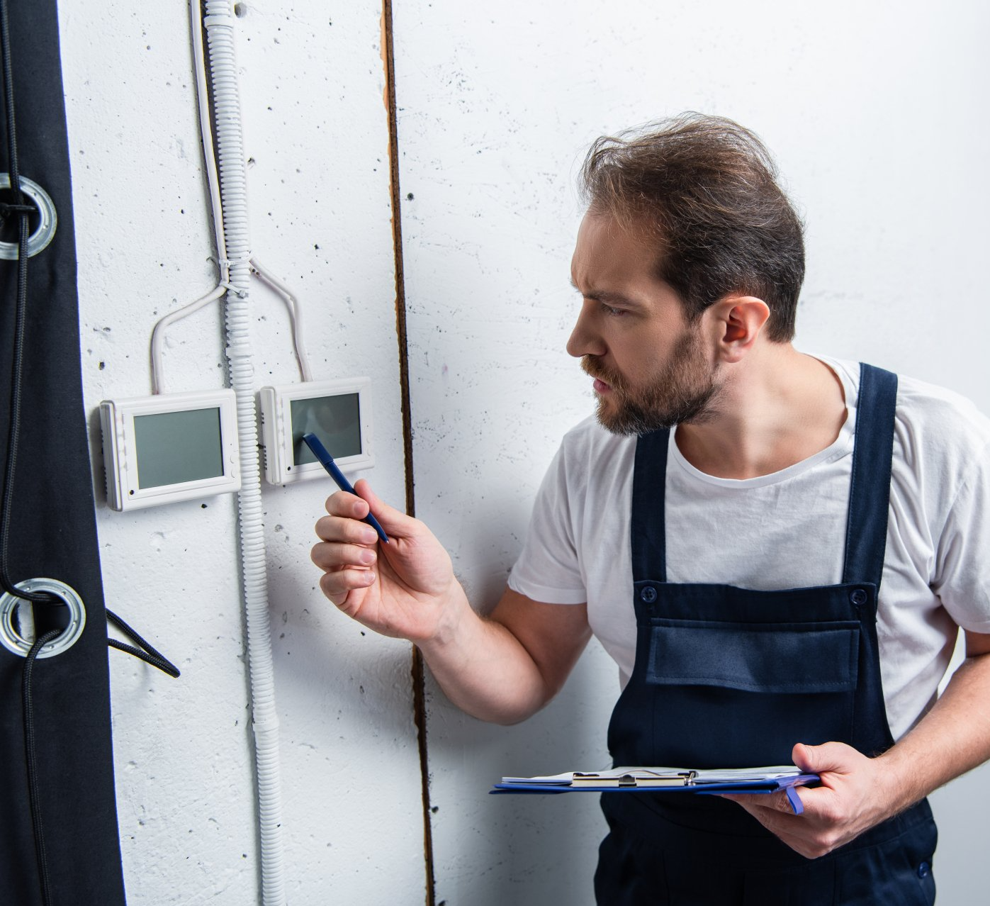 an electrician checking an electrical panel with a clipboard in his hands