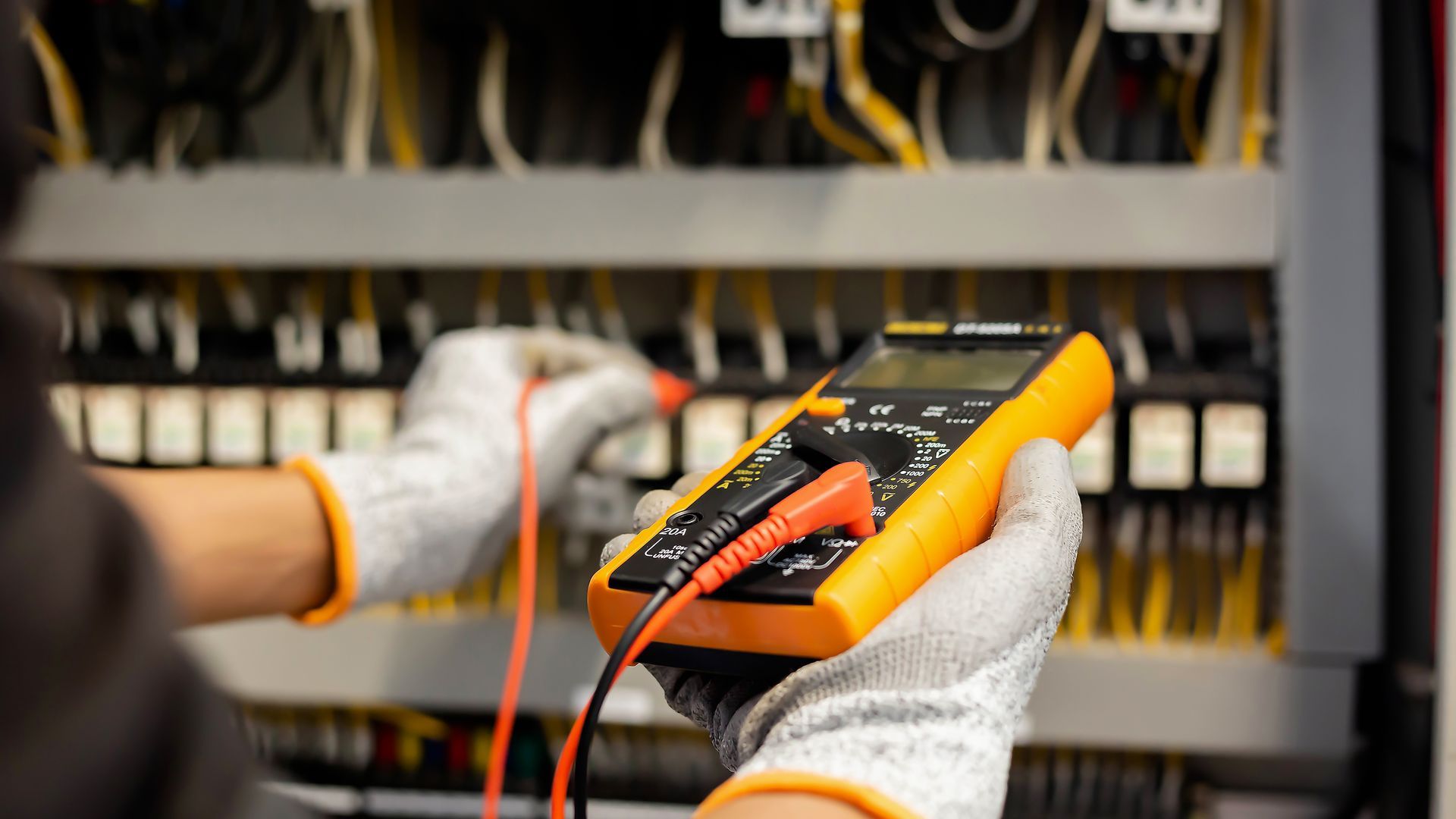 A person is holding a digital multimeter in their hands.