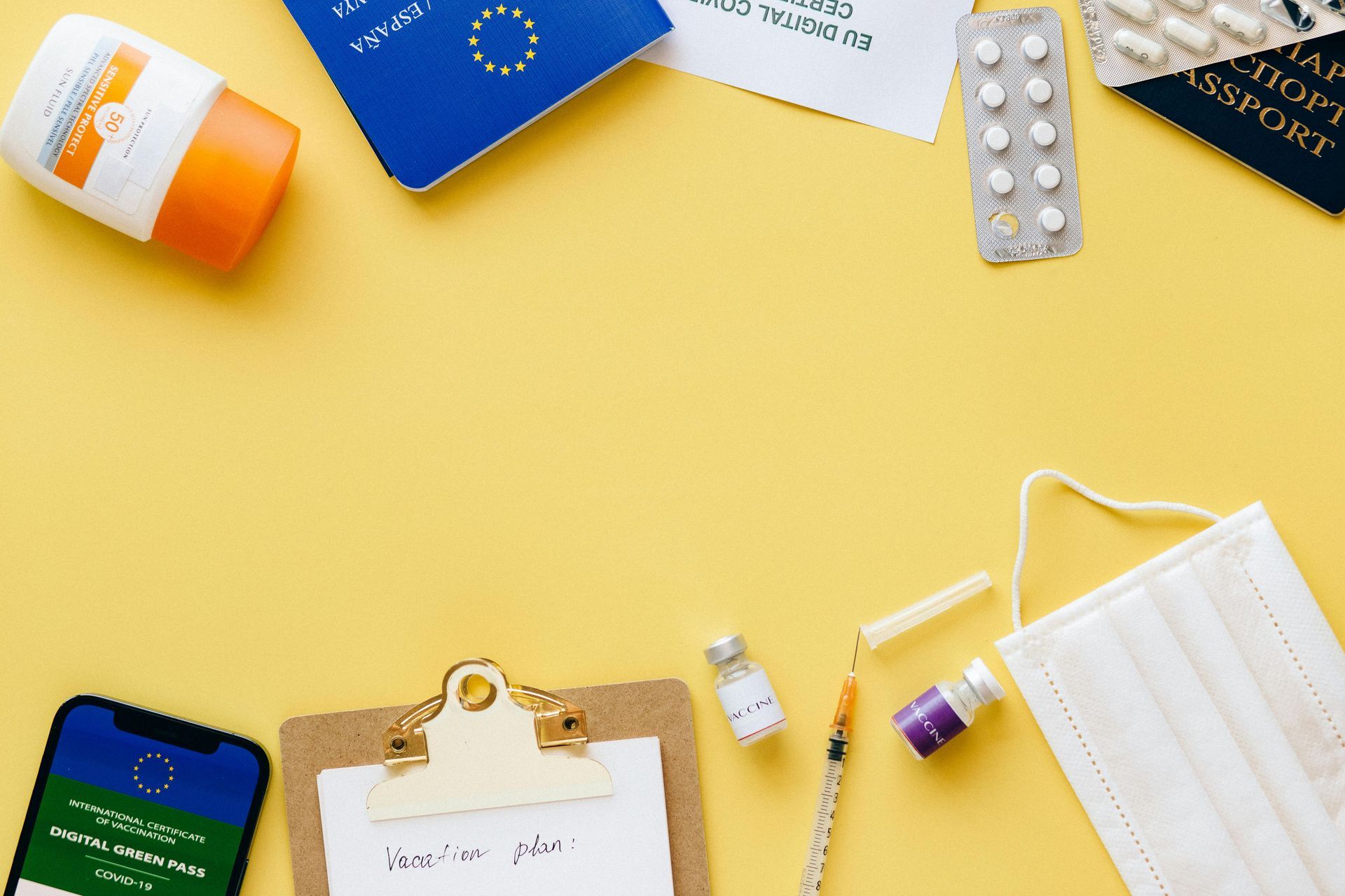 Gelber Hintergrund mit Reisedokumenten, Medikamenten, Impfstoffkomponenten und einer Gesichtsmaske.