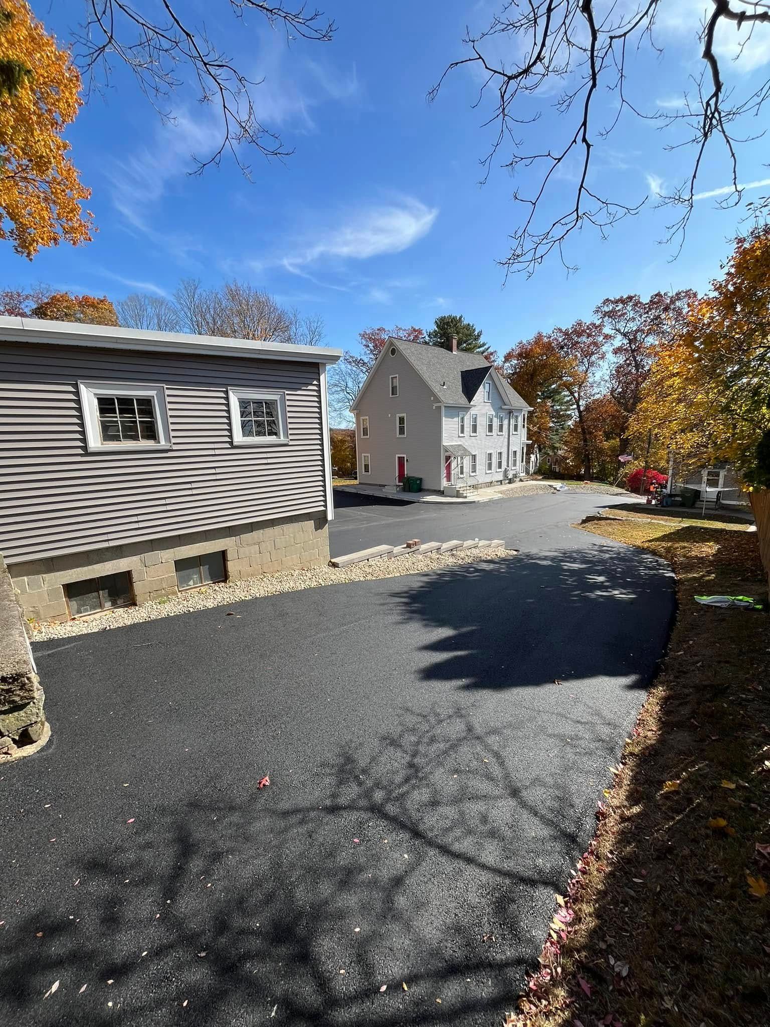 Driveway leading to a two-story house on a sunny day. A detached garage is to the left.
