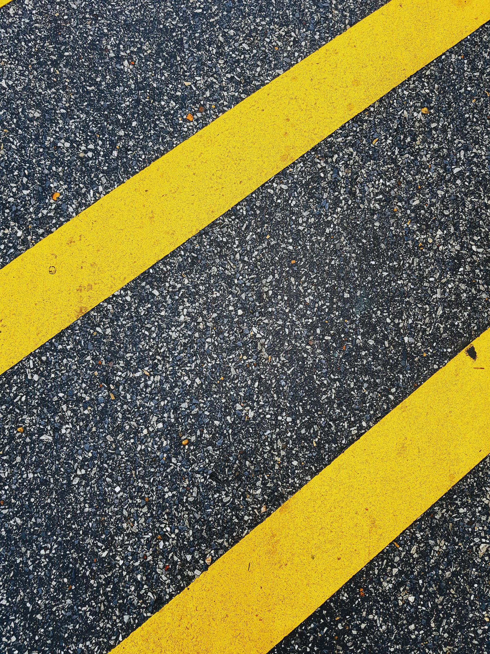 Black asphalt with two diagonal yellow painted lines.
