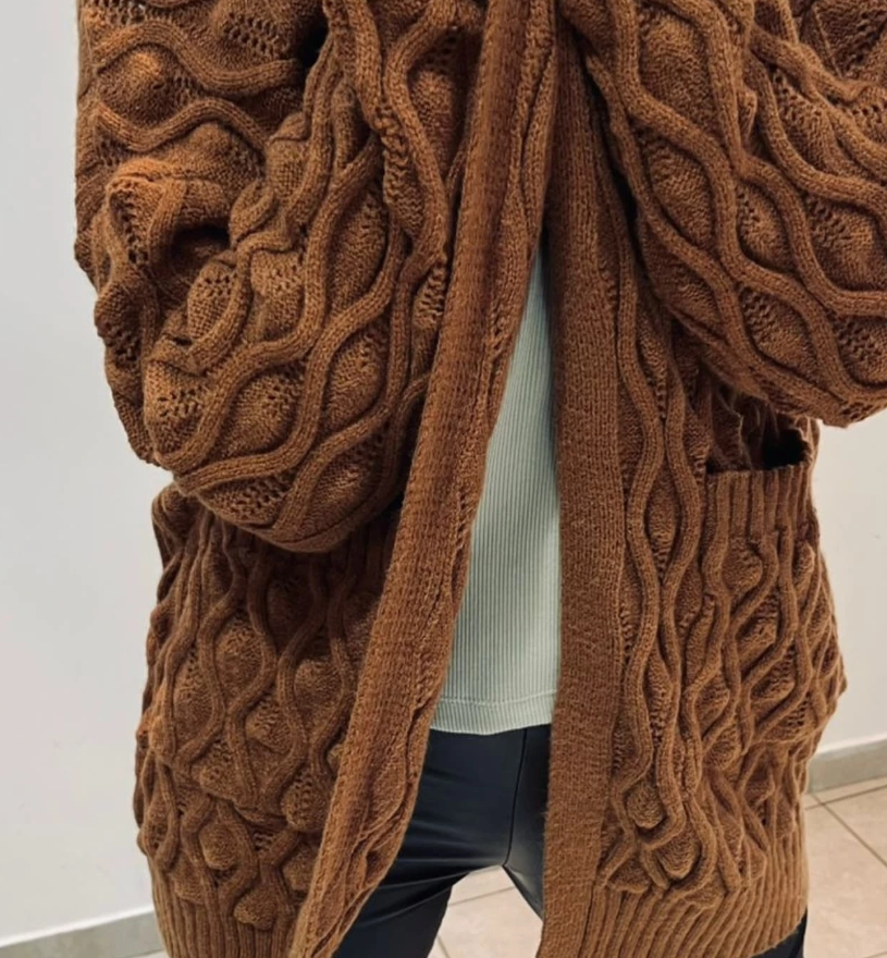 Cárdigan de punto trenzado marrón con bolsillos, para llevar sobre una camisa blanca y un pantalón negro.