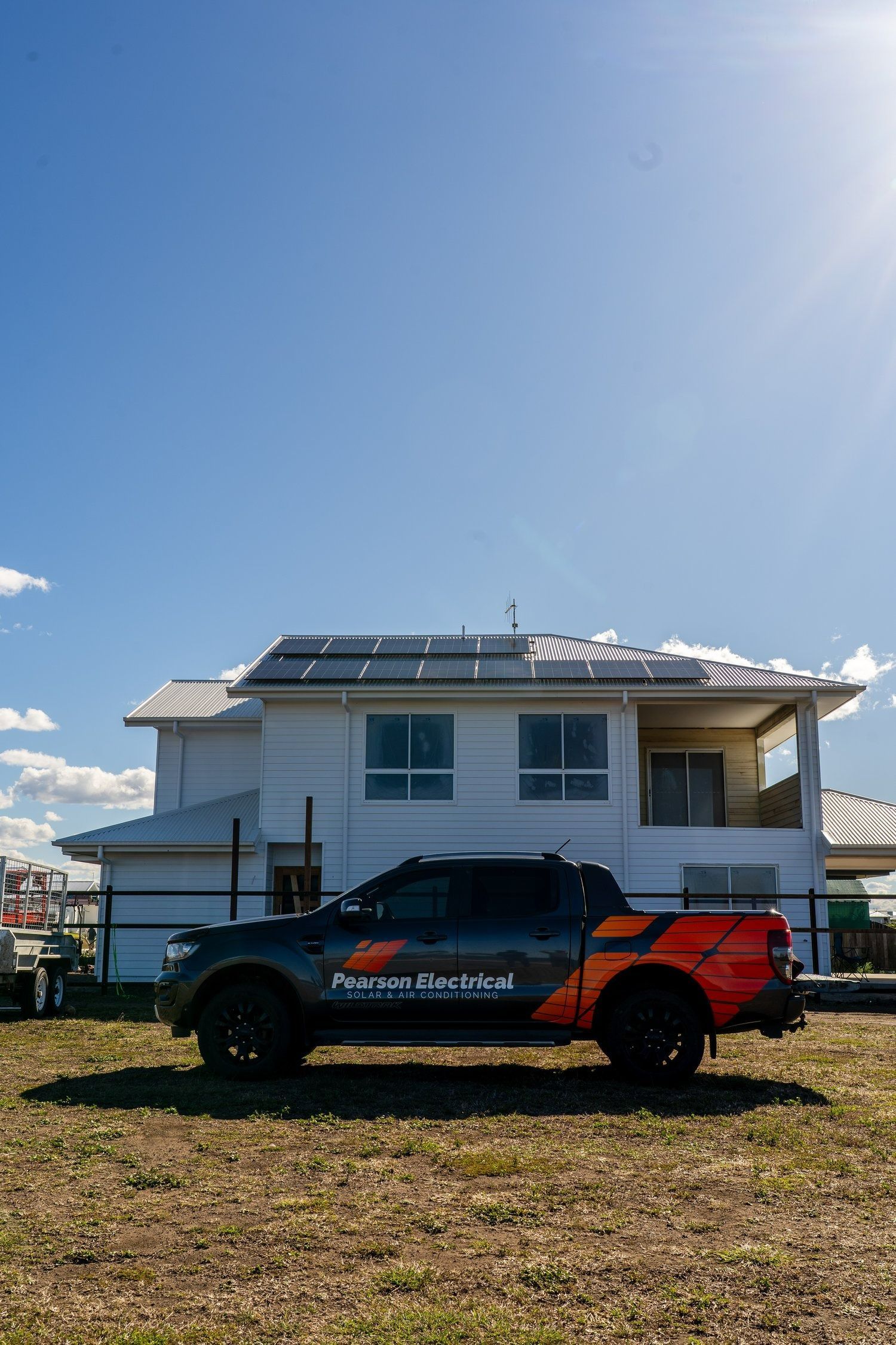 Truck With Orange Decals Parked in Front of a House — Pearson Electrical Solar and Airconditioning in Bundaberg Central, QLD