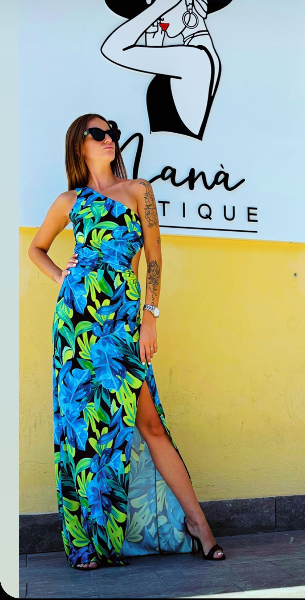 Una donna con un vestito blu e verde è in piedi davanti a un cartello che dice lana tique