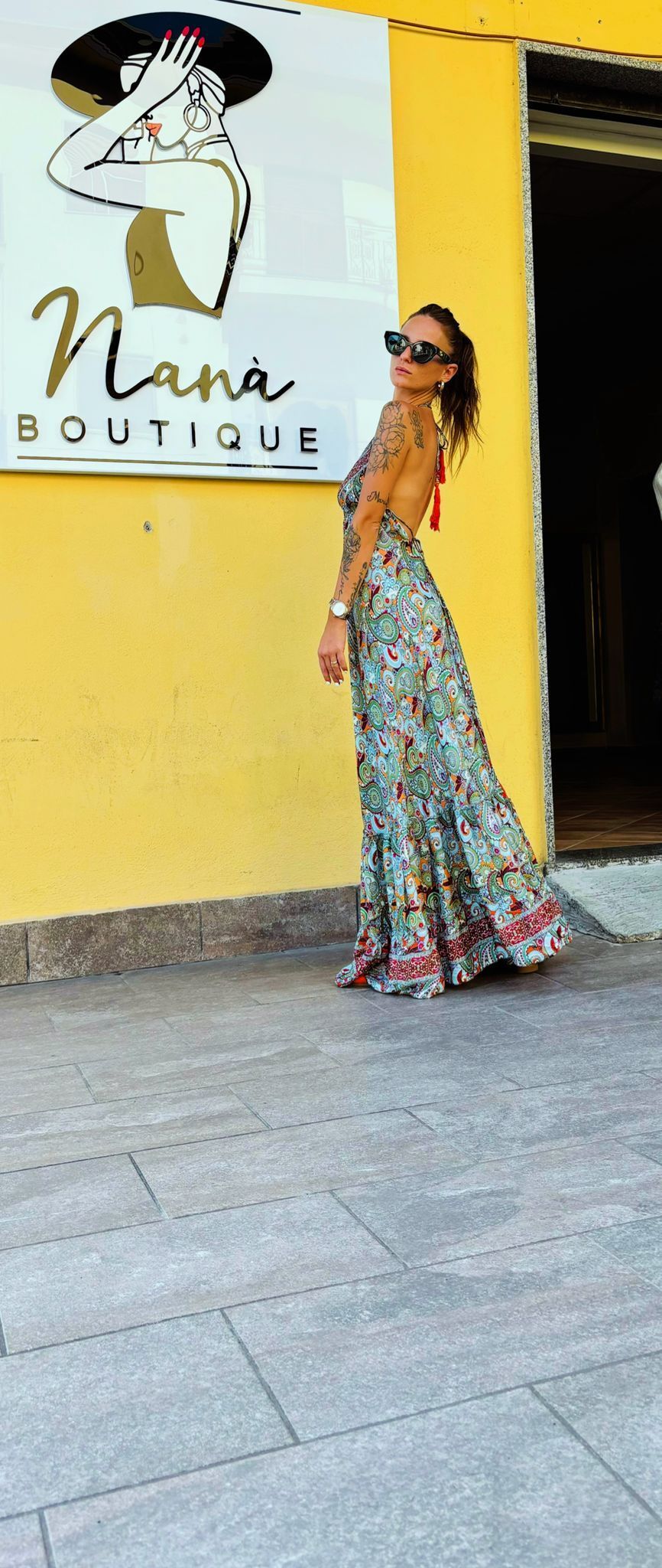 Una donna con un lungo abito è in piedi davanti a un edificio giallo.