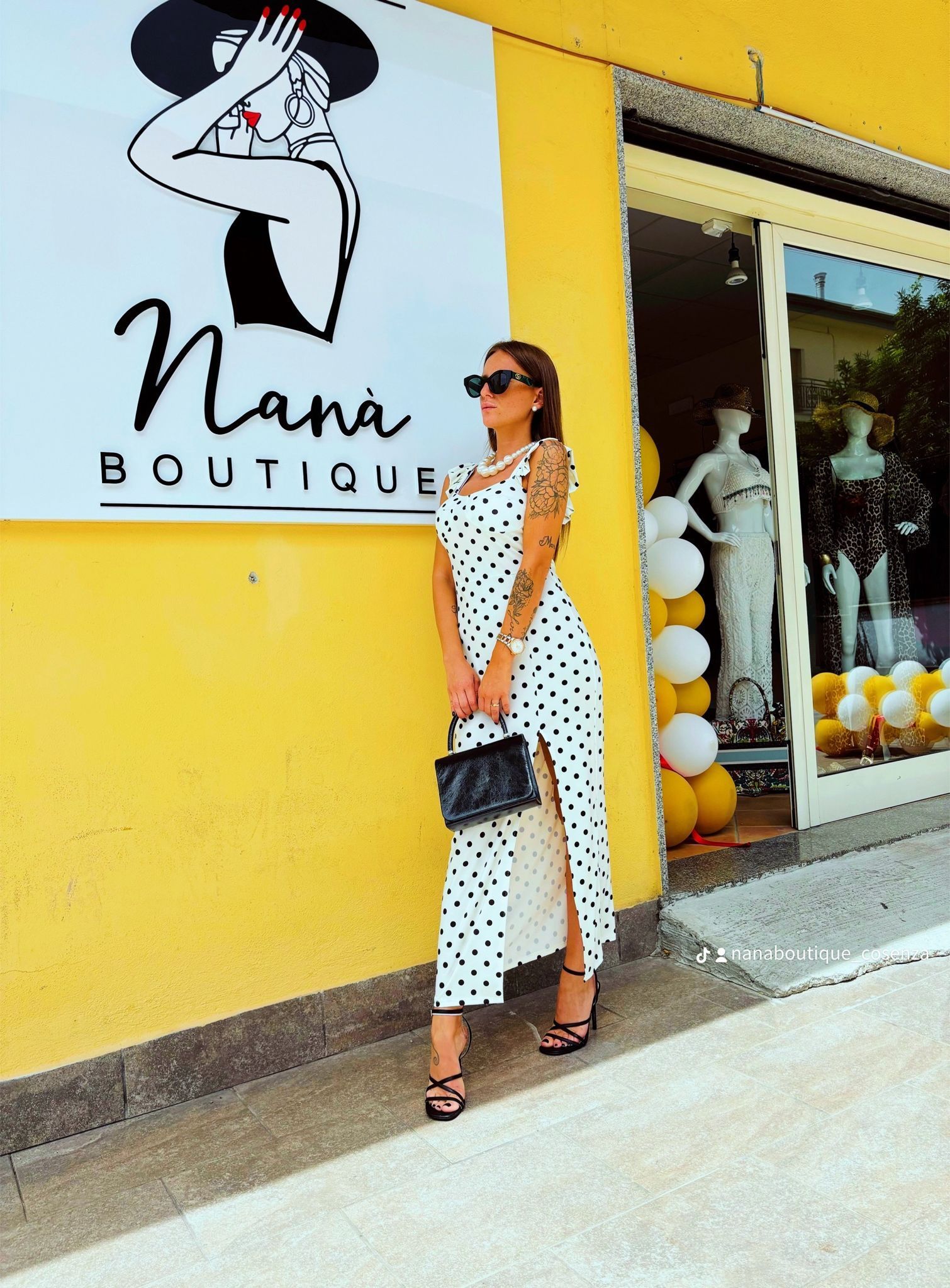 Una donna con un vestito a pois è in piedi davanti a una boutique di nonne