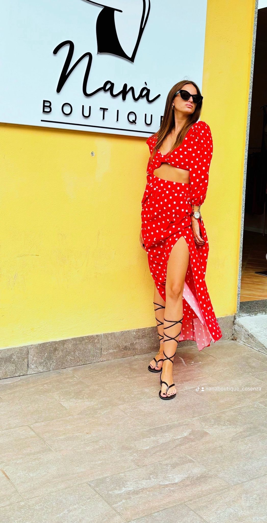 Una donna vestita di rosso è in piedi davanti a un edificio giallo.