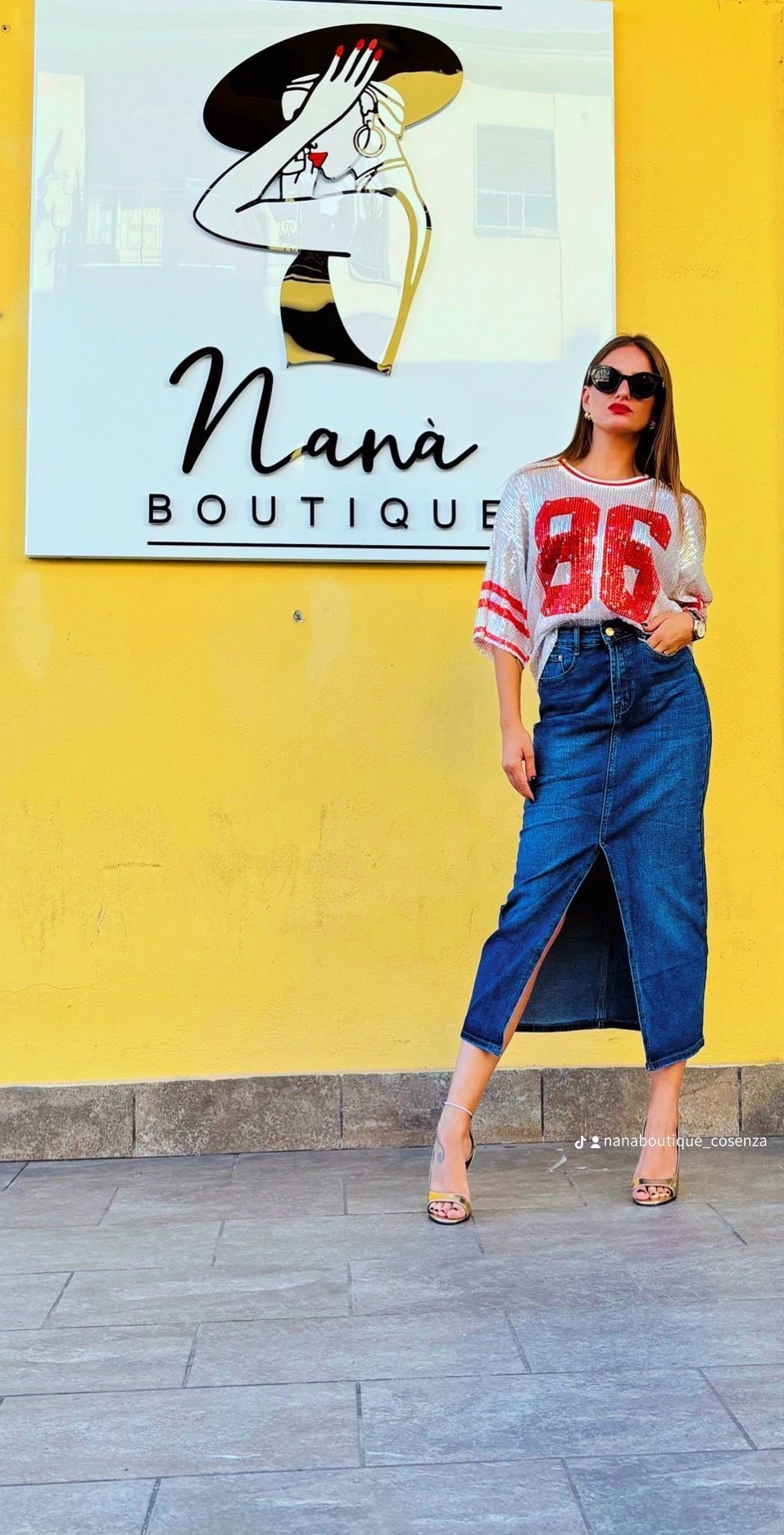 Una donna è in piedi davanti al cartello di una boutique di nana