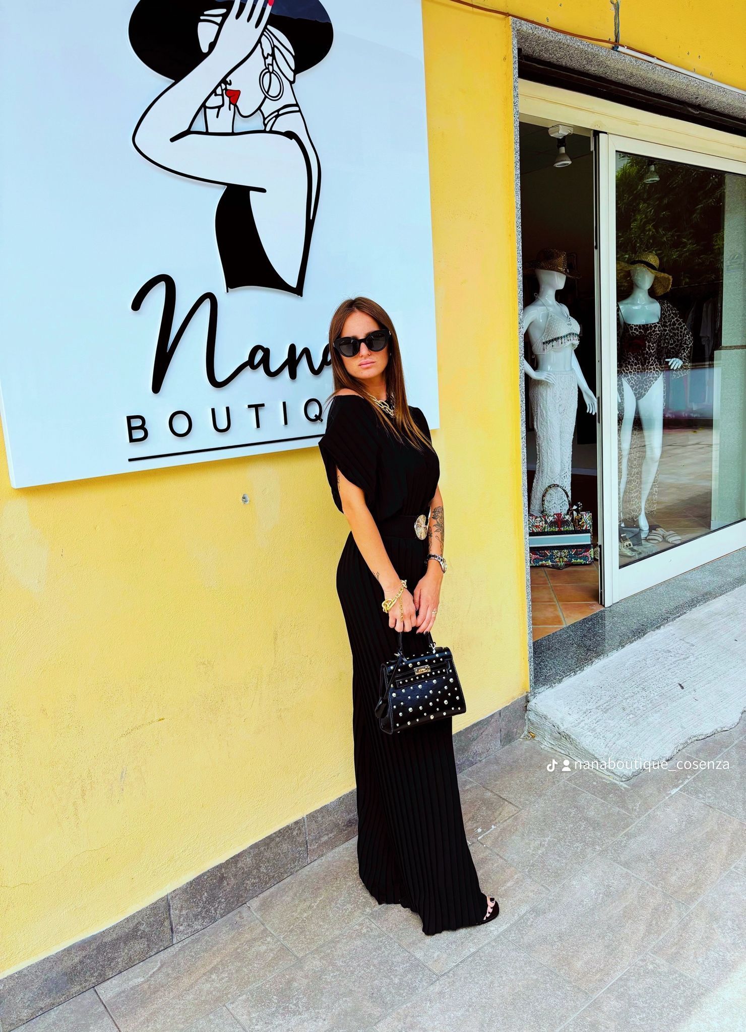 Una donna in abito nero è in piedi davanti a una boutique di nan