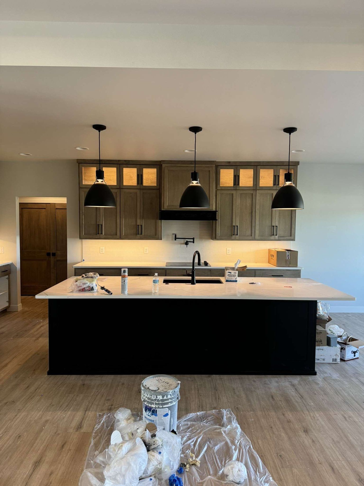 Modern kitchen with a black island, wooden cabinets, and pendant lights.