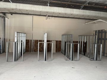 Metal wall studs in various stages of construction in an unfinished room with a concrete floor.