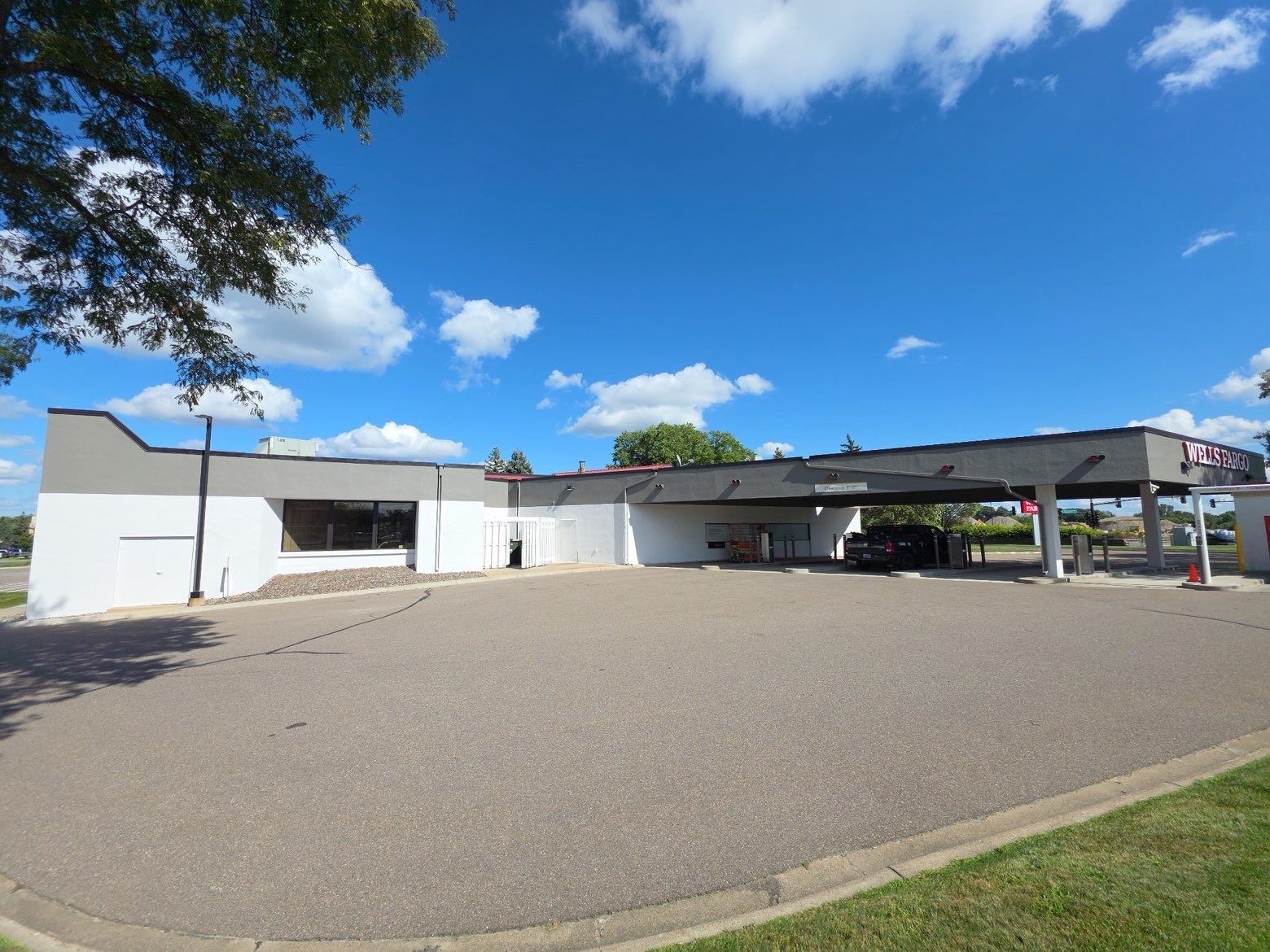 Exterior of a gray and white building with a drive-through under a blue sky and gravel lot.