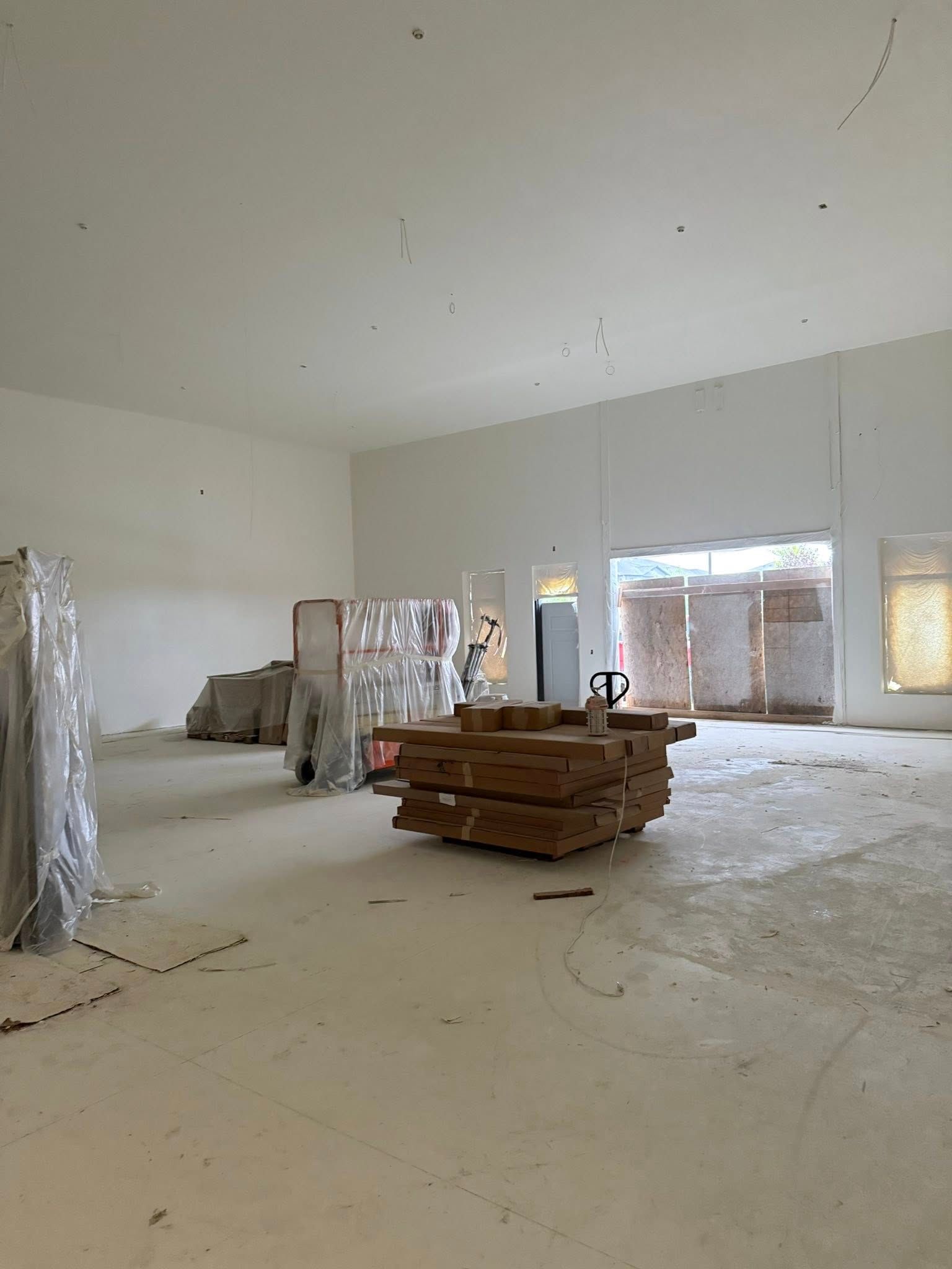 An empty, unfinished interior with stacks of wood and building materials.