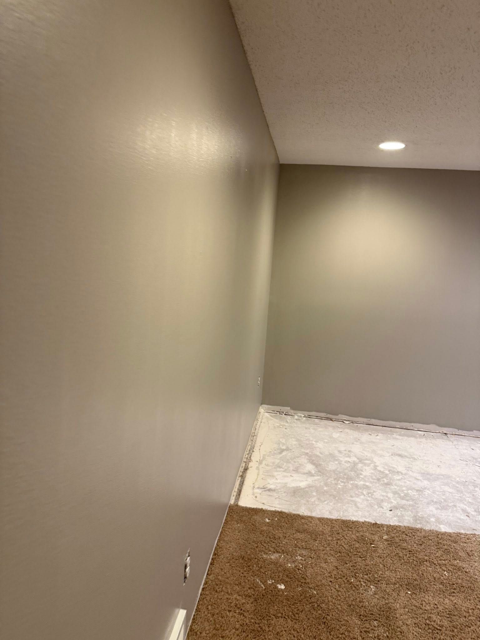 Room with freshly painted gray walls, unfinished floor, and a recessed ceiling light.
