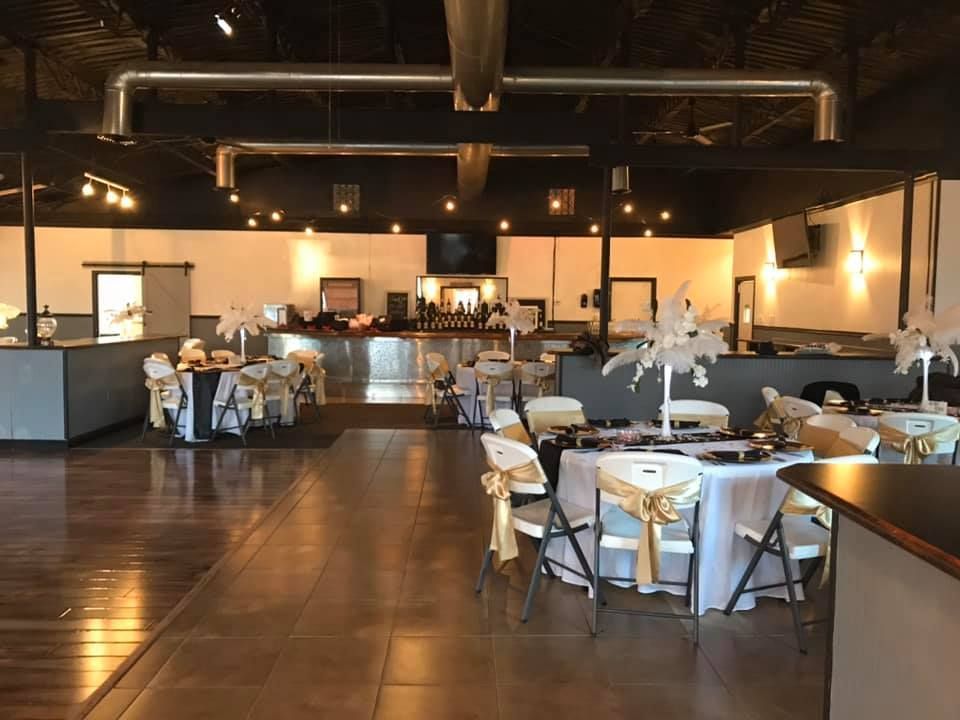 A large room with tables and chairs set up for a wedding reception.