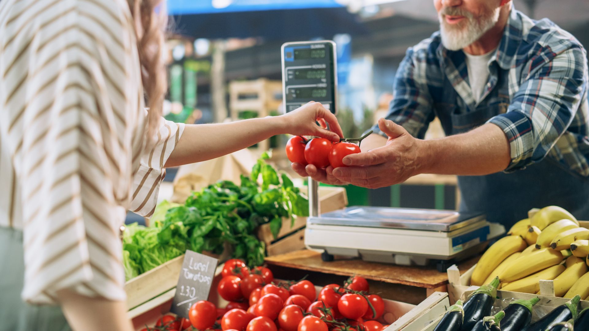 Woman buying tomatoes at a farmer's market from a vendor