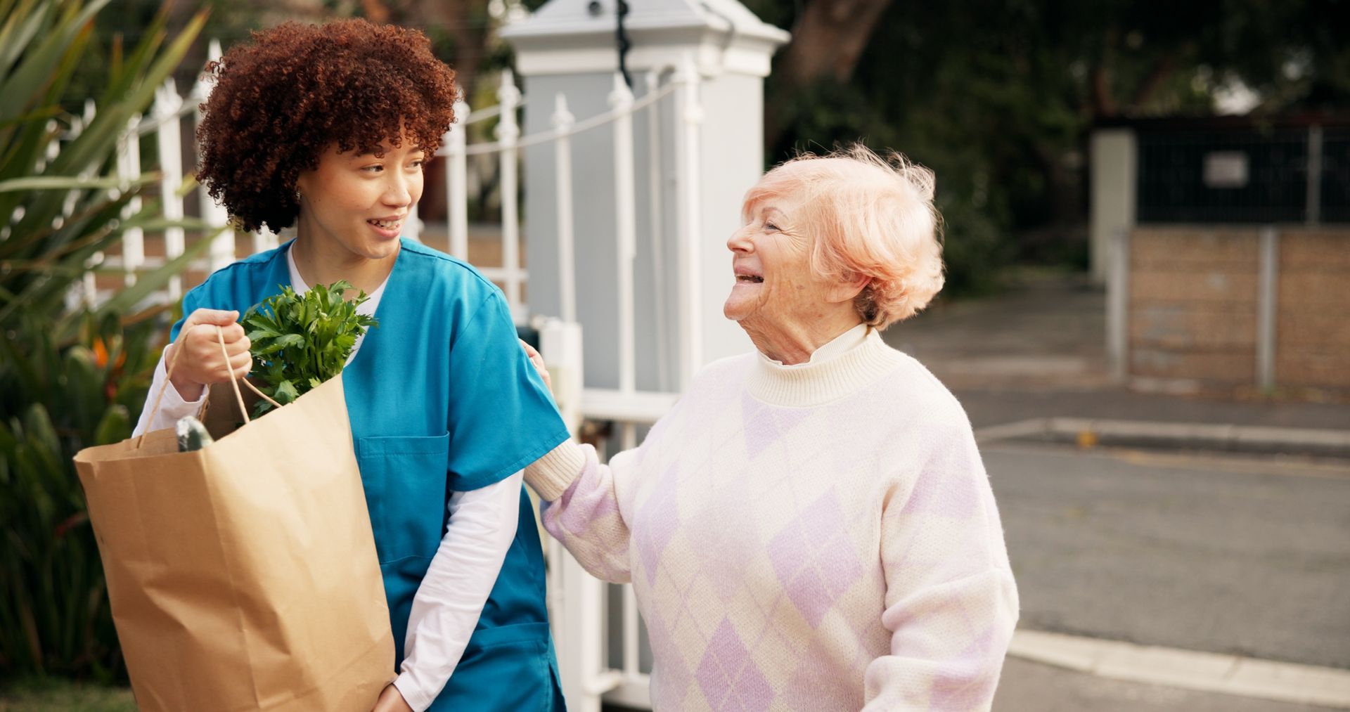 Woman in blue scrubs carries groceries