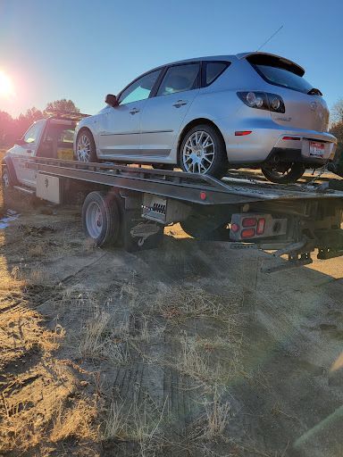 A silver car is being towed by a tow truck.