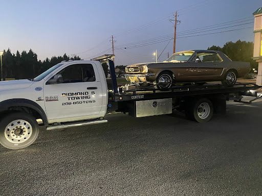 A tow truck is towing a mustang on the back of it.