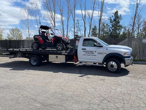 A white tow truck is towing a red atv.