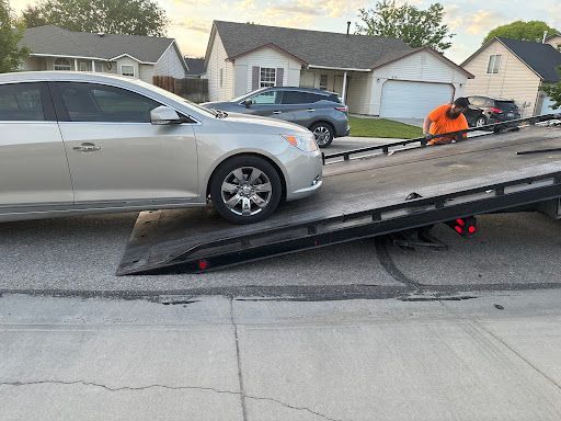 A silver car is sitting on top of a tow truck.