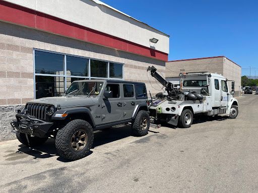 A jeep and a tow truck are parked in front of a building.