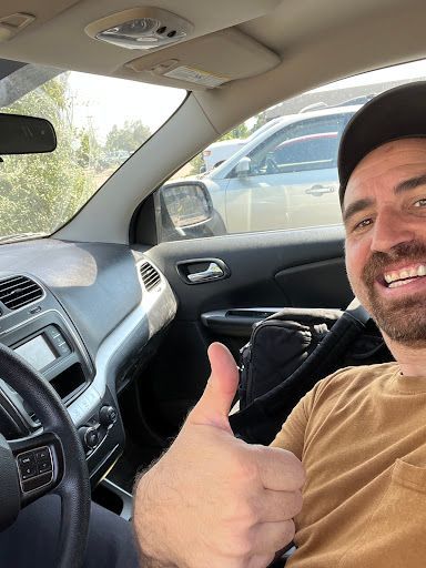 A man is giving a thumbs up while sitting in a car.