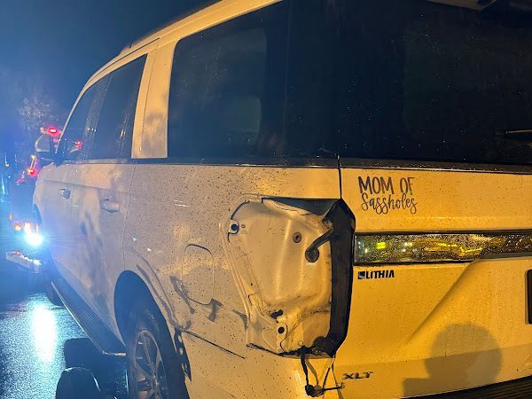 A white van with a sticker on the back that says mom of sunshine.