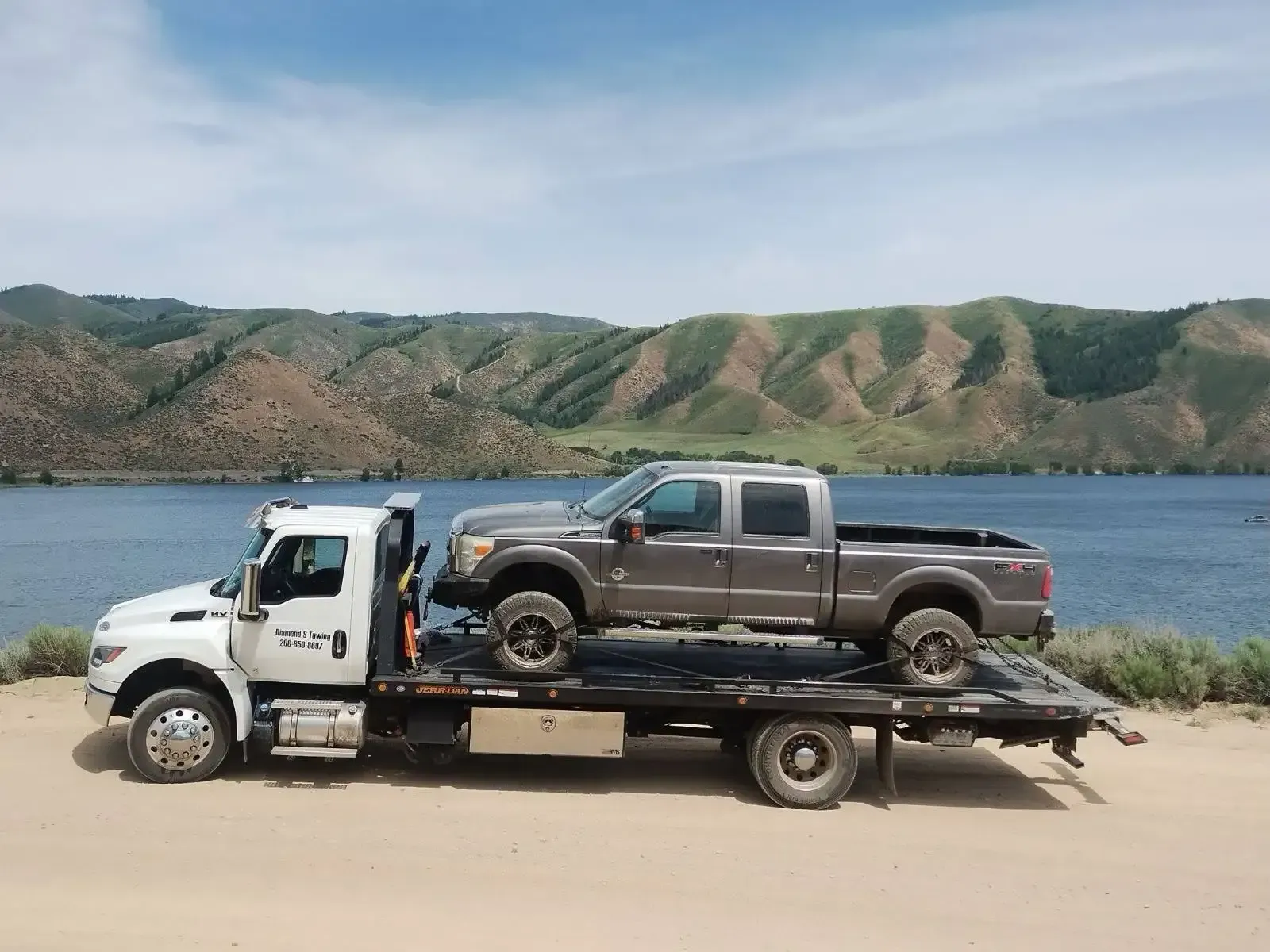 Two trucks are sitting on top of a tow truck.