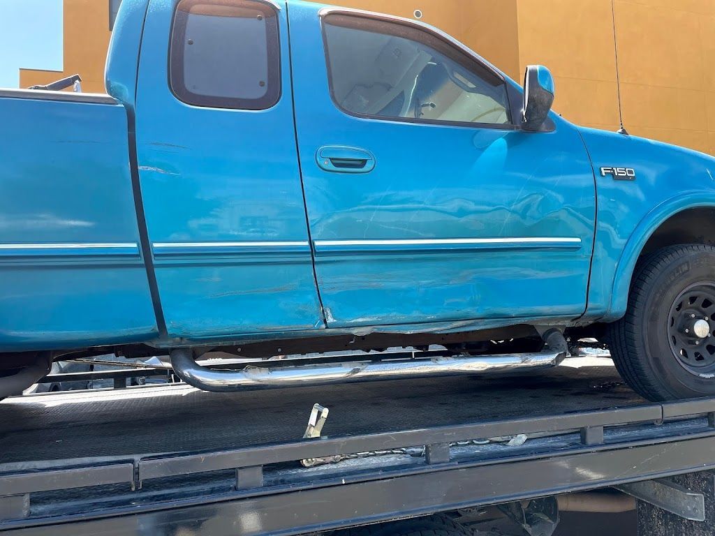 A blue truck is sitting on top of a tow truck.