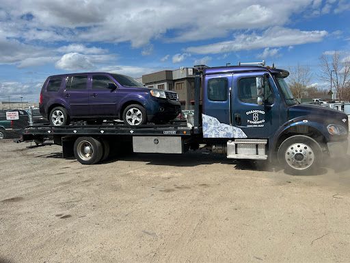 A purple suv is being towed by a tow truck.