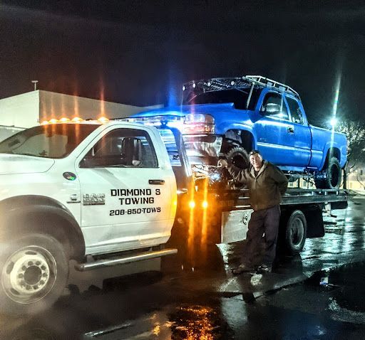 A blue truck is being towed by a diamond towing truck