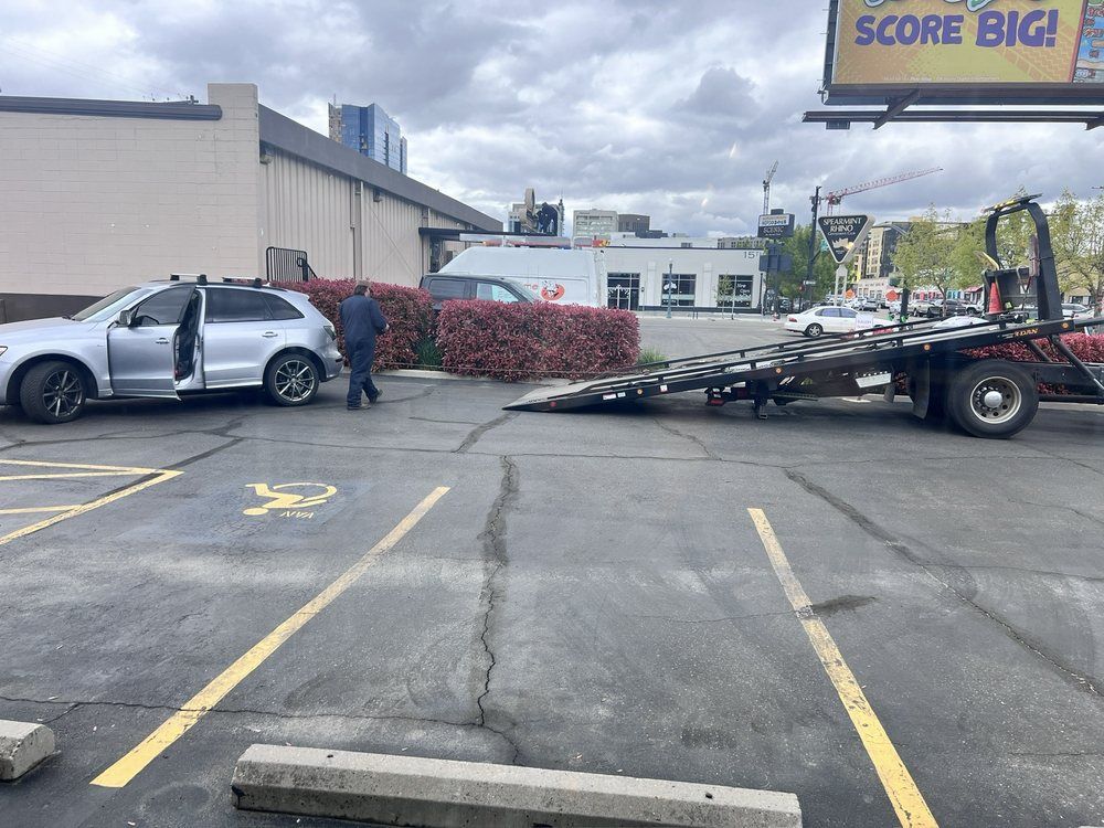 A tow truck is towing a car in a parking lot.